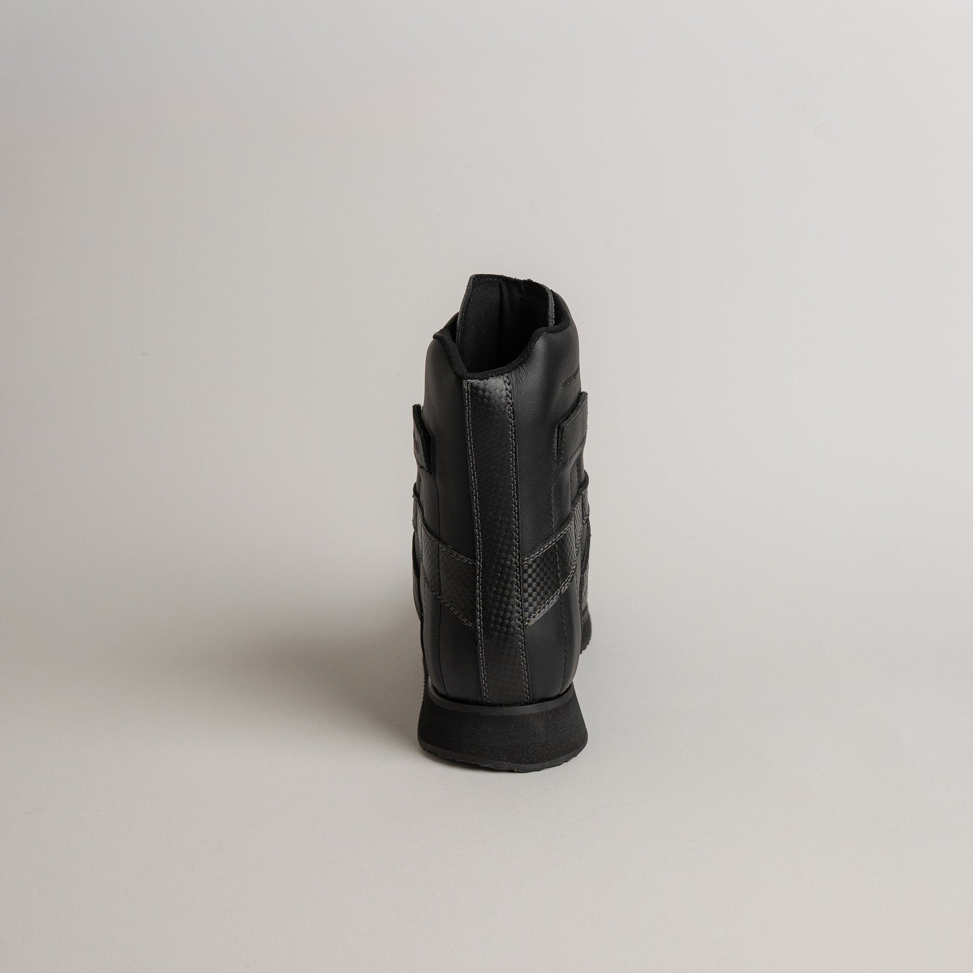 Ein schwarzer Kuenzli Schuh aus Leder, Rückansicht auf hellem Hintergrund.