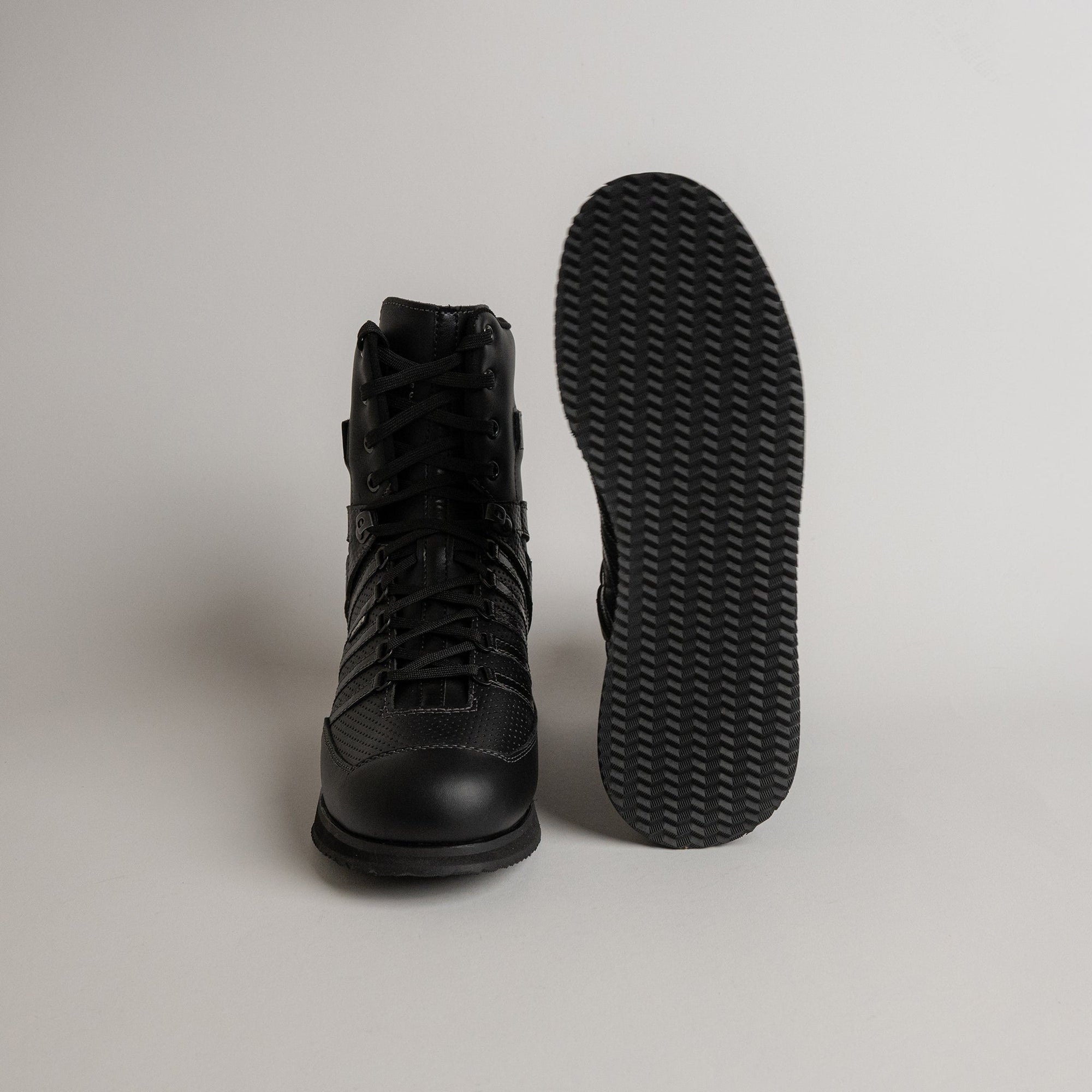 Schwarzer Kuenzli Schuhe Stiefel mit rutschfester Sohle auf grauem Hintergrund.