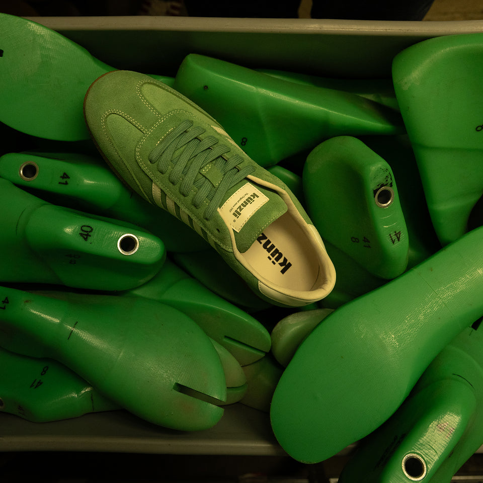 Grüner Kuenzli Schuh auf grünen Schuhleisten, ideal für sportliche Aktivitäten.